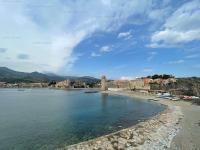 a beach with a town and a lighthouse in the water at 4PA72 - Magnifique appartement pour 4 dans résidence avec piscine et parking in Collioure