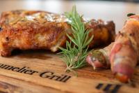 エセキエル・モンテスにあるHOTEL MERLOT INNの木のまな板に肉とローズマリーを添えて