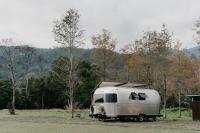 a white trailer parked in a field next to trees at The Silence Manor in Ruisui