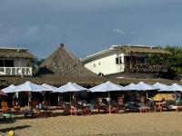 a group of tables and chairs with umbrellas on a beach at Che Zipolite Hostel & Beach Club in Zipolite