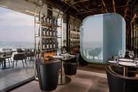 een restaurant met uitzicht op de oceaan en tafels en stoelen bij The Promenade Luxury Wellness Hotel in Riccione