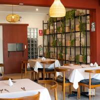 a dining room with tables and chairs and potted plants at Rua Hoteles Talara in Talara