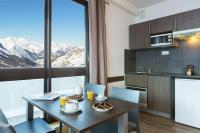 eine Küche und ein Esszimmer mit einem Tisch und einem Fenster in der Unterkunft SOWELL RESIDENCES Pierre Blanche in Les Menuires