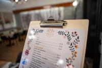 a restaurant menu with flowers on a clipboard at WRZOS resort & wellness in Węgierska Górka