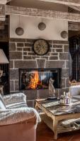 a living room with a stone fireplace with a table at Les Maisons de Montagne - Chez Marie in Pailherols