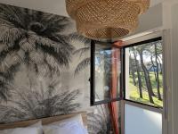 a bedroom with a window and a palm tree wallpaper at Douce brise à Seignosse-2 min à pied de la plage in Seignosse