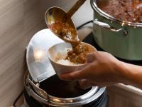 仙台APA Hotel TKP Sendai Eki Kita的一个人手里拿着一碗食物放在烤面包机里