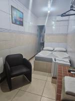 una pequeña habitación con una cama y una silla en Arahra Hotel, en Aparecida de Goiania