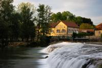 a waterfall in front of a building next to a river at Moulin de Chappes in Chappes