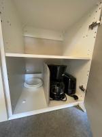 a cupboard with a coffee maker and a microwave at Au petit paradis in Camiers