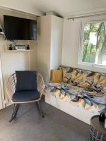 a room with a couch and a chair and a tv at Au petit paradis in Camiers