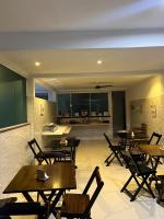 a restaurant with wooden tables and chairs and a kitchen at Pousada Portico de Buzios in Armacao dos Buzios