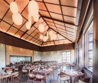 a dining room with tables and chairs and windows at Sajjan Bagh Resort Kumbhalgarh in Kumbhalgarh
