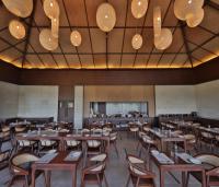 a restaurant with wooden tables and chairs and lights at Sajjan Bagh Resort Kumbhalgarh in Kumbhalgarh