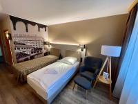 a bedroom with a bed and a chair and a lamp at Hotel &amp; Restaurant Bergfried in Saalfeld
