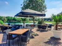 un patio con tavoli, sedie e un ombrellone di Gezellige vakantiewoning met sauna in Ewijk bij Nijmegen - recreational only no workers a Ewijk