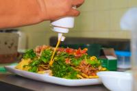 Hotel El Cocobolo Food&Rest Room 6 B&B WiFi AC Pkg Free Swimmingpool في ليبيريا: شخص يسكب الصلصة على السلطة في طبق