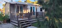 a small cabin with a wooden deck with a table at Camping Aux Portes De Cassis in La Bédoule
