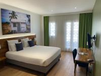 a hotel room with a bed and a desk and a bed and a desk at Hôtel Exsel Créolia in Saint-Denis