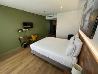 a bedroom with a white bed and a desk with a lamp at Hôtel Exsel Créolia in Saint-Denis