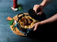 una persona sosteniendo un tazón de comida con pasta en Campanile Valence Sud, en Valence