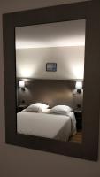 a mirror reflecting a bedroom with a white bed at HÔTEL ROYAL MONTREUIL in Montreuil