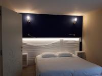 a bedroom with a white bed with a black headboard at Hôtel Le Claridge in Propriano