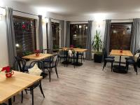 Un restaurante con mesas y sillas de madera y ventanas. en Hotel Astra Tajemniczy Ogród, en Poznan
