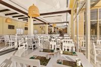 un restaurante con mesas blancas y sillas blancas en Al Hamra Village Hotel, en Ras al Khaimah