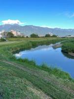 a river in a field with mountains in the background at 5 Loaves 2 Fish B&amp;B in Hualien City