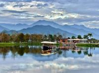 a boat on a lake with mountains in the background at 5 Loaves 2 Fish B&amp;B in Hualien City