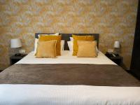 a bedroom with a large bed with yellow pillows at Hôtel Arcadia in Lannion