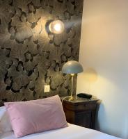a bed with a pink pillow and a lamp on a table at Hotel Mirabeau in Tours