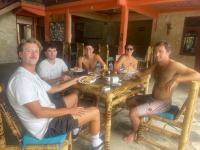Un grupo de hombres sentados en una mesa comiendo comida en SuperSuck Hotel, en Maluk