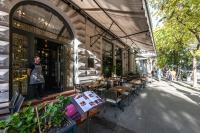 un uomo in piedi fuori da un ristorante con tavoli e sedie di Hotel Moments Budapest by Continental Group a Budapest