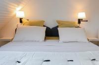 a bed with white sheets and yellow pillows in a room at Calme, Confort et Propreté in Vittel