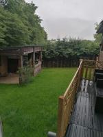 a backyard with a wooden deck with a grass yard at Chalet - l&#39;Endoxyle in Froid-Chapelle