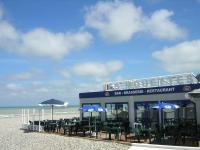 a restaurant on the beach with chairs and umbrellas at "Le JUGUILI" 46m2 en front de Mer - 4 personnes - animaux OK - Entièrement rénové - Haut de gamme - wifi in Mers-les-Bains