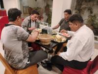 Un gruppo di uomini seduti intorno a un tavolo che mangiano cibo di Elite Homes ad Aurangabad