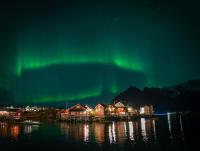 una imagen de la aurora boreal sobre una ciudad en Henningsvær Rorbuer, en Henningsvaer