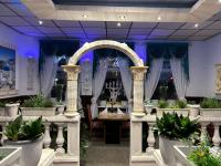 a banquet hall with potted plants and an arch at Hotel Restaurant Rhodos in Elsterwerda