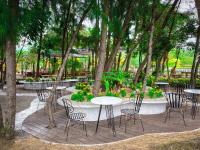 eine Gruppe von Tischen und Stühlen in einem Park mit Bäumen in der Unterkunft Seagate Bungalow Quy Nhon in Quy Nhon