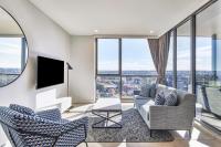 Una sala de estar con un sofá y sillas y ventanas. en Meriton Suites Liverpool, en Liverpool