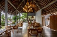 un ristorante con tavoli e sedie e un lampadario di Premadhan Cottage Canggu a Canggu