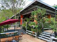 Bangnu Greenery Resort في Takua Thung: مطعم فيه كراسي وطاولات ومظلة حمراء