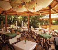 um restaurante ao ar livre com mesas, cadeiras e guarda-sóis em Fiori Hotel em Gouviá