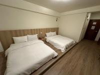 two beds in a room with white sheets at Yawan Hotel in Wenquan