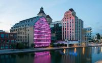 a building is lit up with pink lights in the water at Joyau de Pantin in Pantin