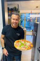 T8- Willa Tetmajera Gdynia في غدينيا: رجل يحمل بيتزا في متجر