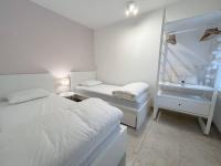 a white bedroom with two beds and a window at Appartement met 2 slaapkamers-VAYA G002 in De Panne